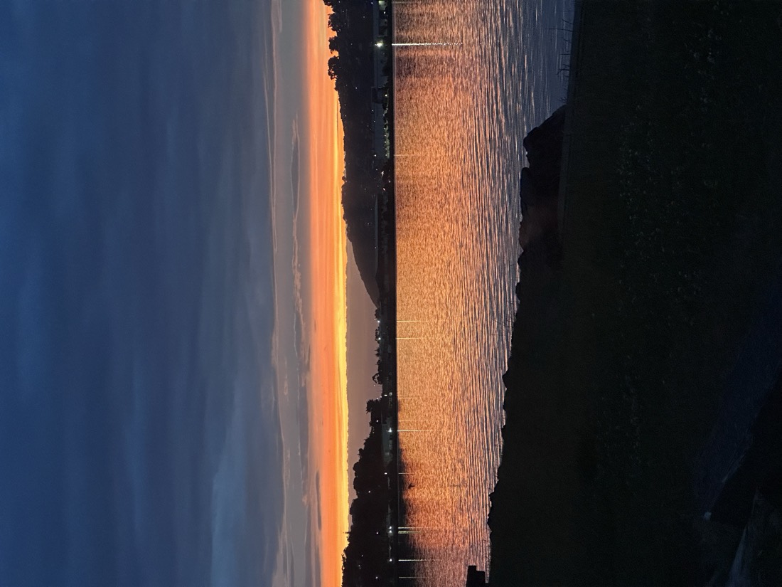 Sunset over the Otago Harbour, Dunedin — orange sky reflected on still water